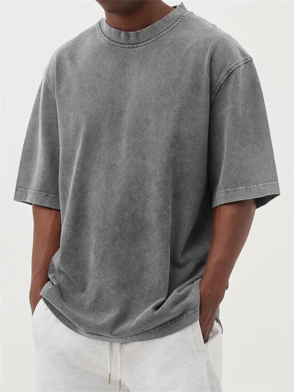 Man wearing a loose fit stone washed distressed t-shirt in a solid colour, showing short sleeves and casual styling.
