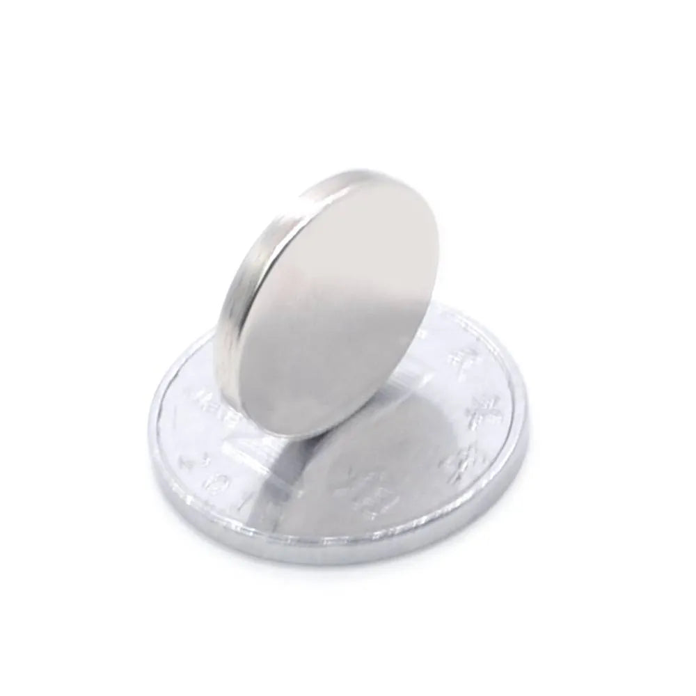 Silver neodymium magnet disc 14x2mm on plain background