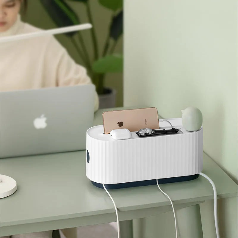 Blue and white plastic cable management box for power strips with lid open showing phone slot and cable holes