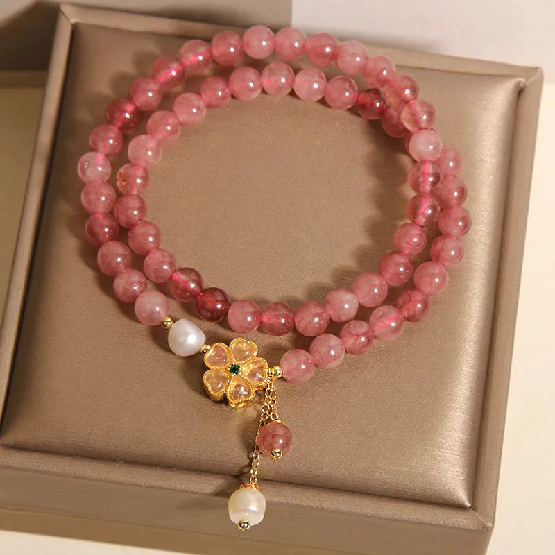 Close-up of a women's bracelet with a strawberry quartz four-leaf clover charm on an alloy chain.
