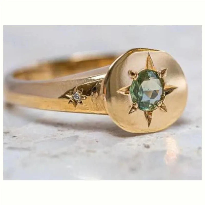Gold-coloured star-shaped ring with a central oval zircon stone on an adjustable band.