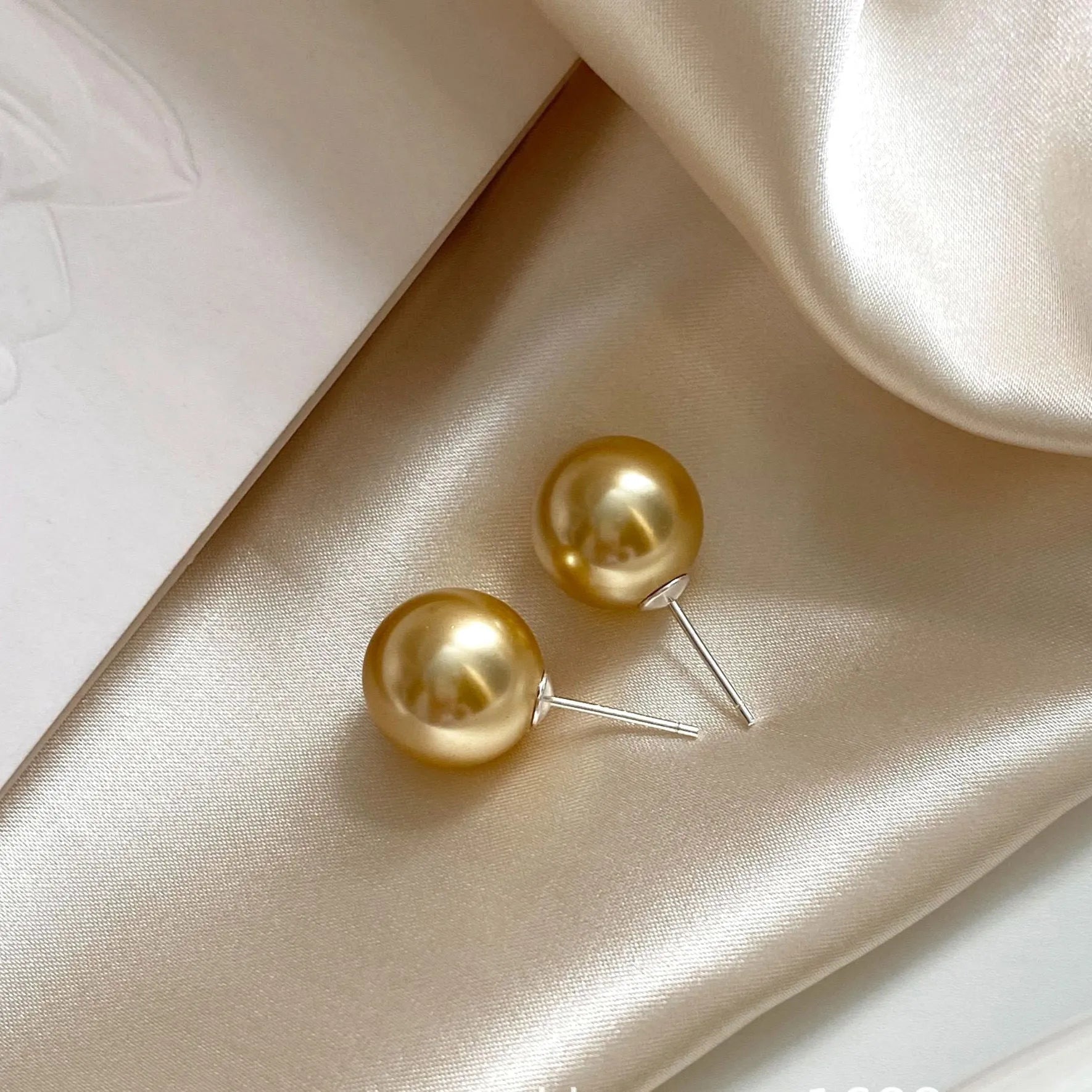 Large pearl stud earrings with geometric silver settings and eight-pointed star motifs