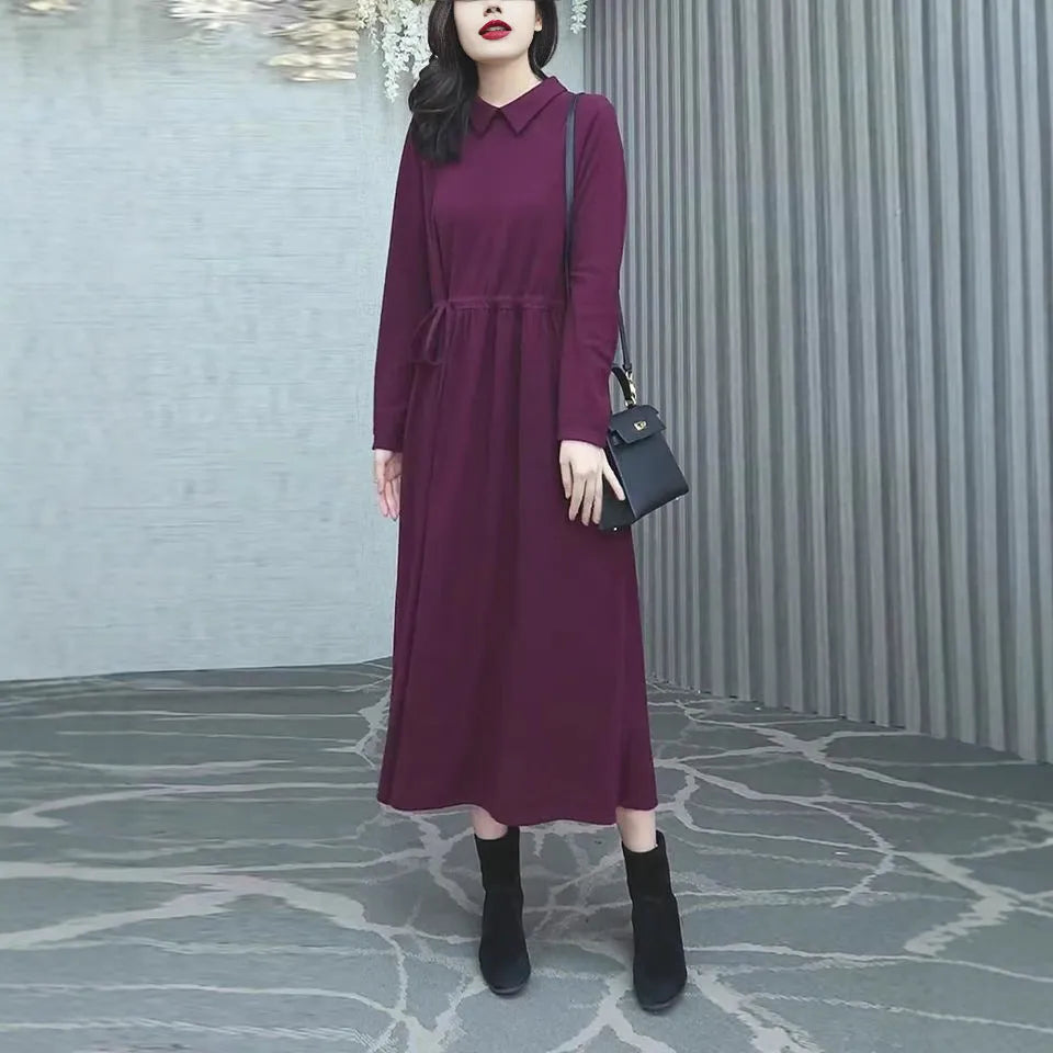 A purplish red plus size long sleeve dress with an ankle-length skirt on a mannequin.