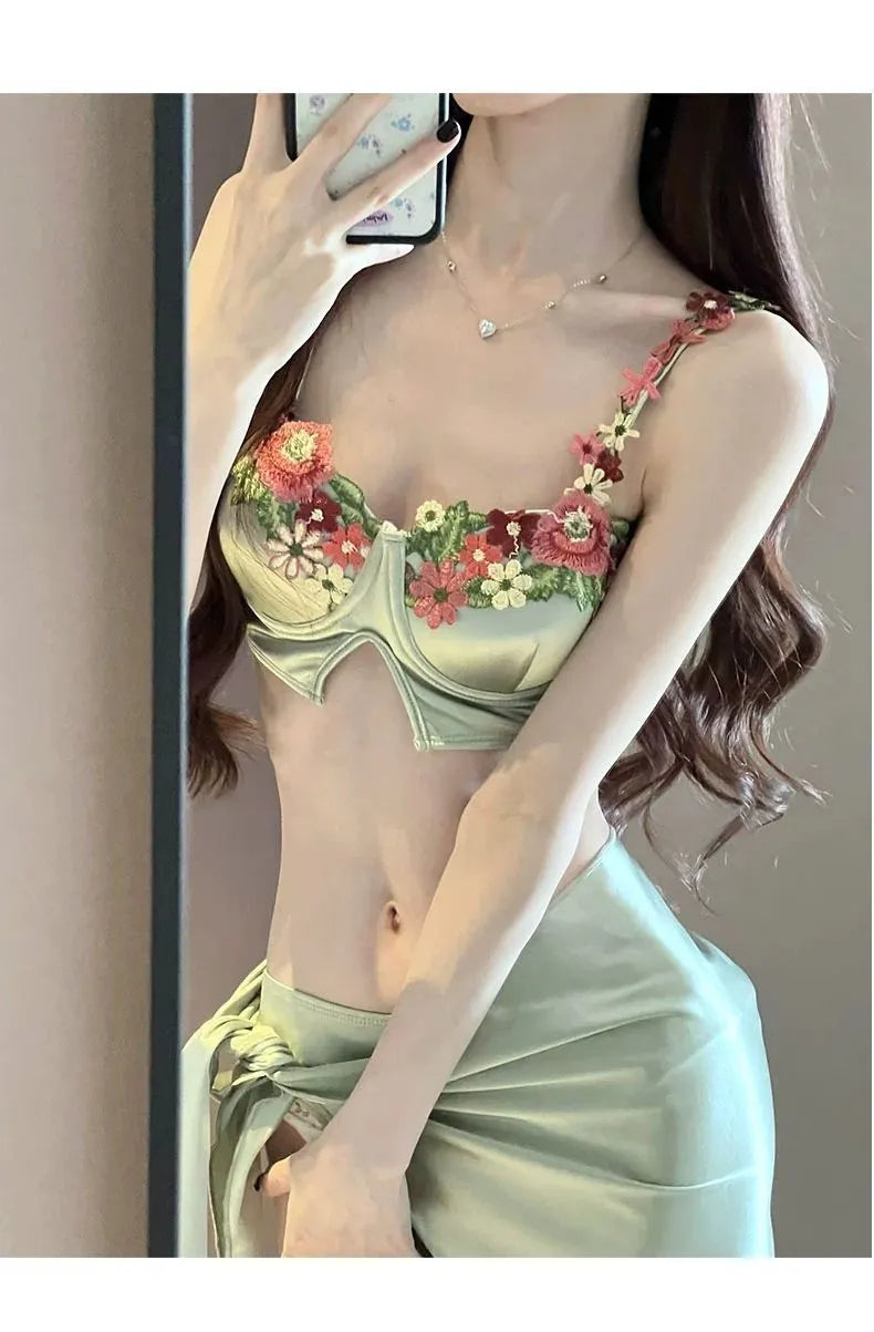 Green women's three-piece bikini swimsuit set with triangle top, briefs, and a short skirt on a mannequin.