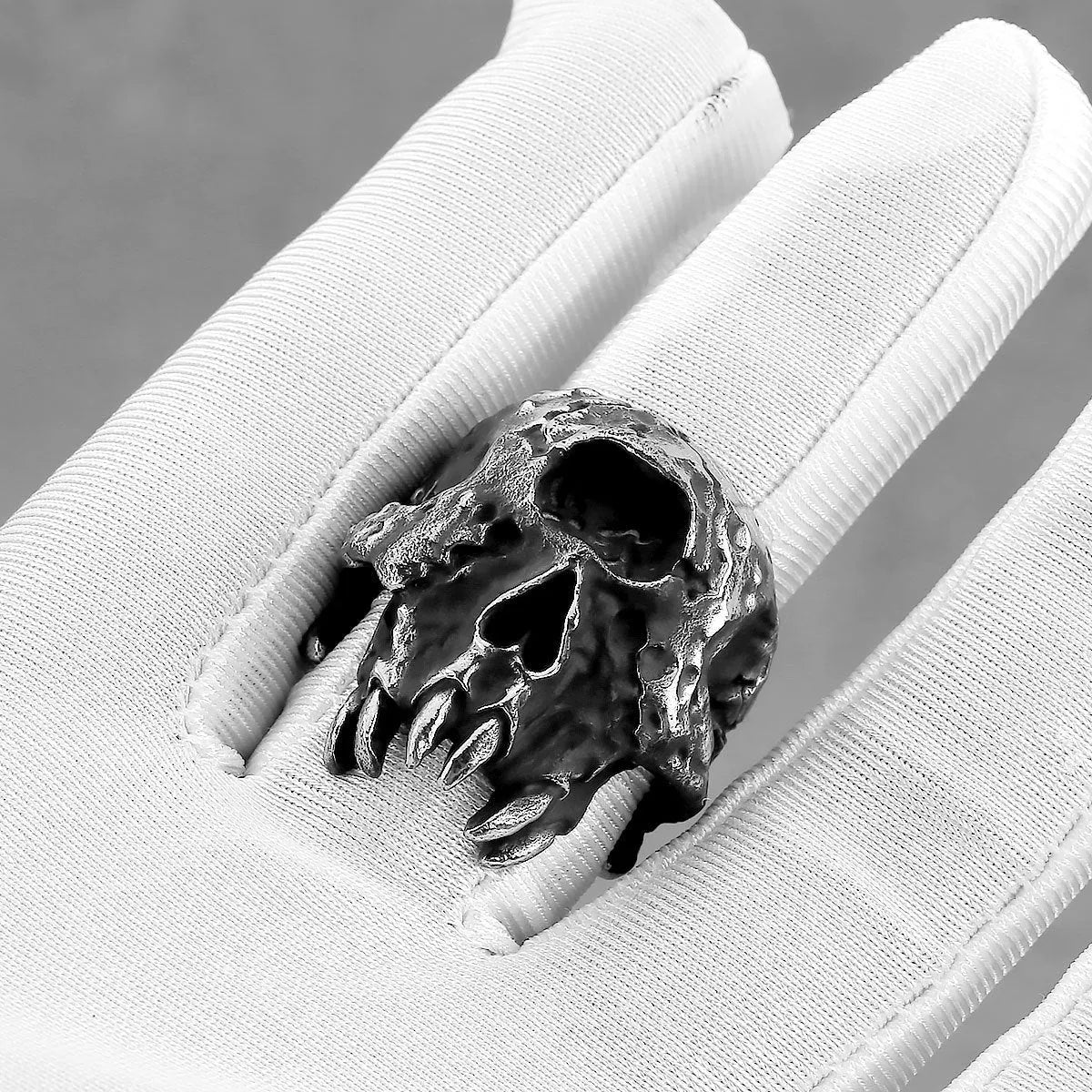 Close-up of a silver-toned alloy ring with a raised one-eyed skull design on a black background.