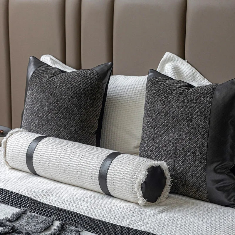 Modern minimalist grey and white plaid bed runner blanket set with matching pillowcase and leather round pillow on a bed.