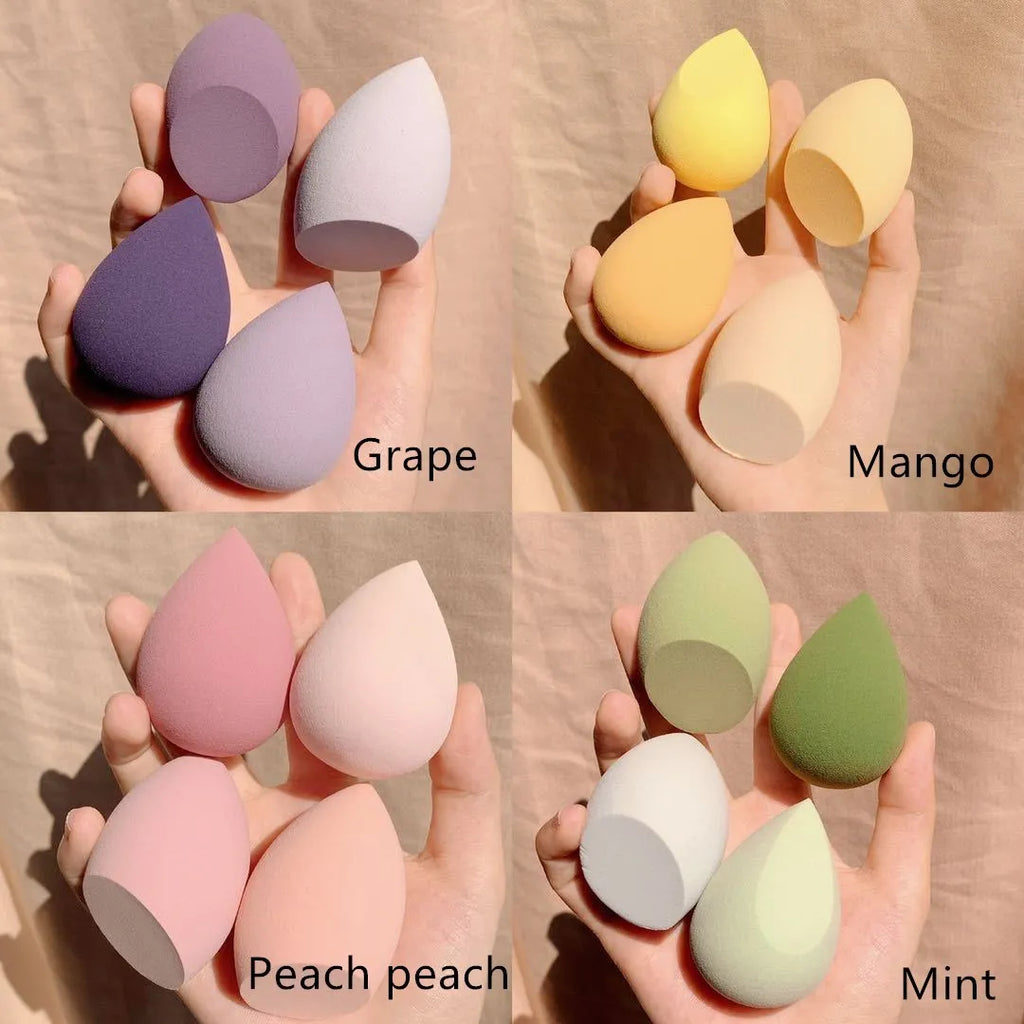 Four makeup sponge eggs in grape, mango, mint, and peach colours on white background