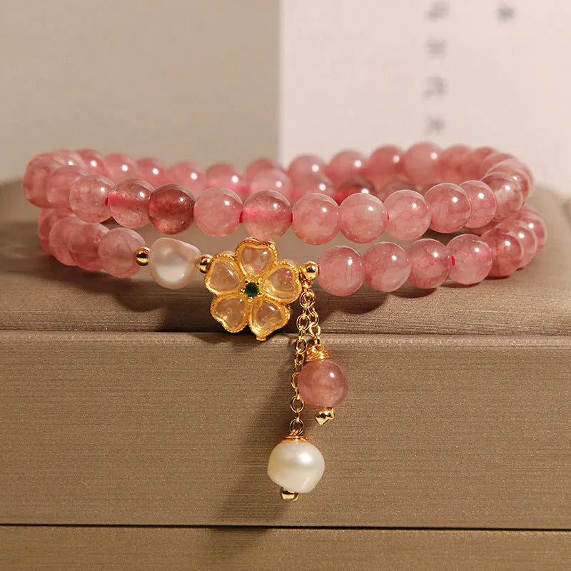 Close-up of a women's bracelet with a strawberry quartz four-leaf clover charm on an alloy chain.
