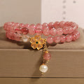 Close-up of a women's bracelet with a strawberry quartz four-leaf clover charm on an alloy chain.