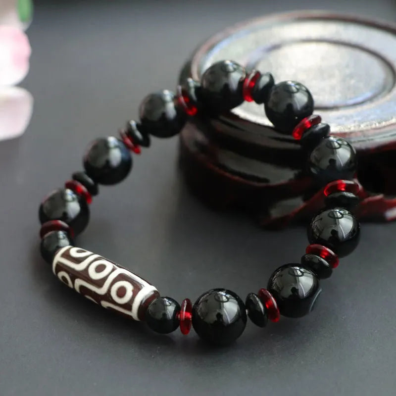 Hand-woven black agate dzi bead bracelet with 11mm geometry beads on a wrist.