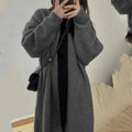 A woman wearing a loose, dark grey knitted chenille cardigan with a 3D-effect texture.