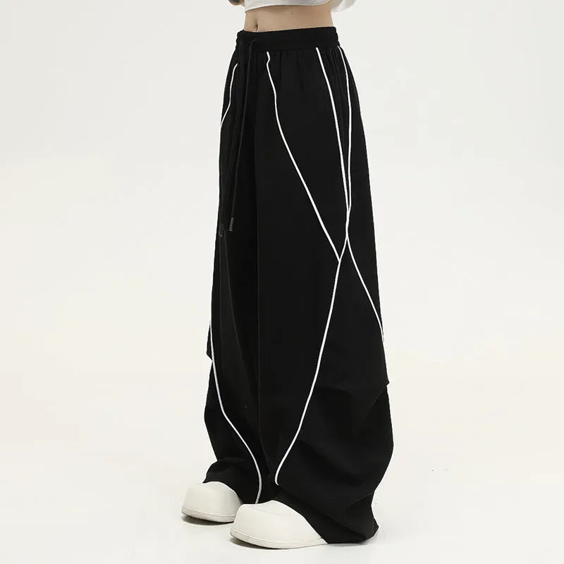 Black striped wide-leg sports pants with pleated detail on a mid-waist, loose fit.