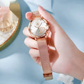 Rose-coloured women's watch with mesh strap, showing dial colour options of white, black, blue, red, pink, and green.