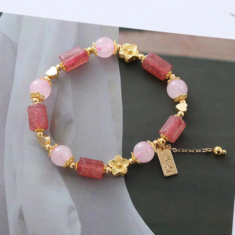 Pink strawberry crystal bracelet with star-shaped beads and a small heart charm on a white background