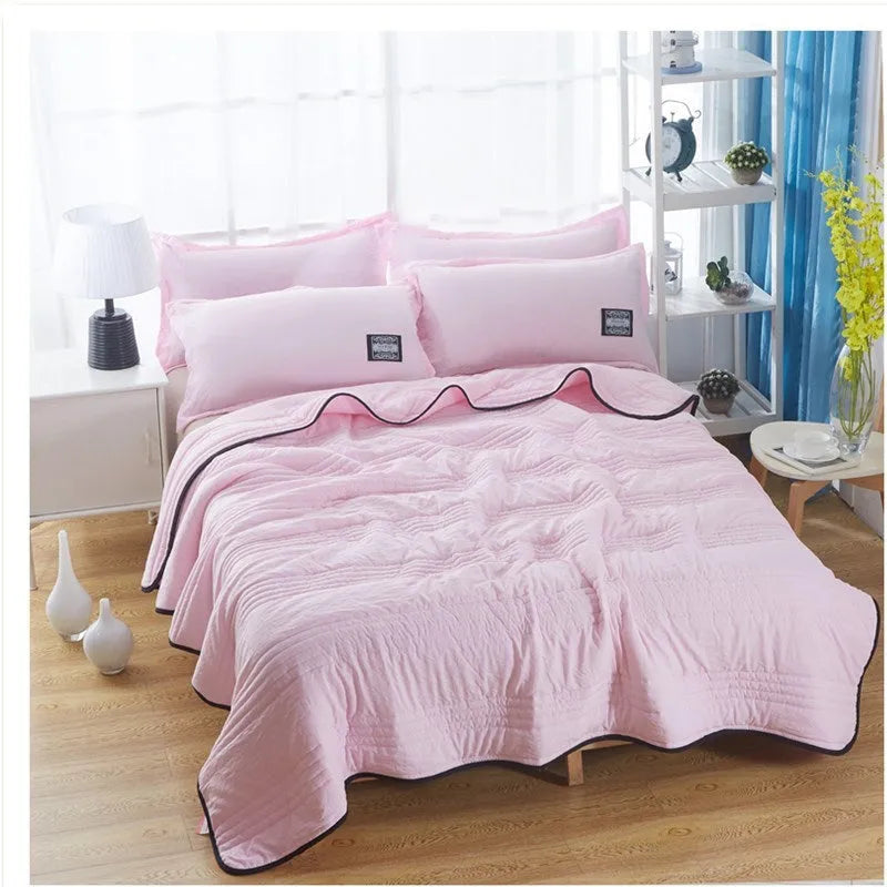 Plain colour seersucker summer cooling quilt shown in light pink on a bed.