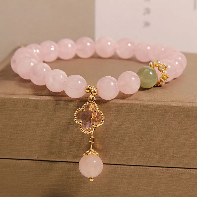 Pink crystal bracelet with a four-leaf clover pendant and rhinestone details on an alloy chain.