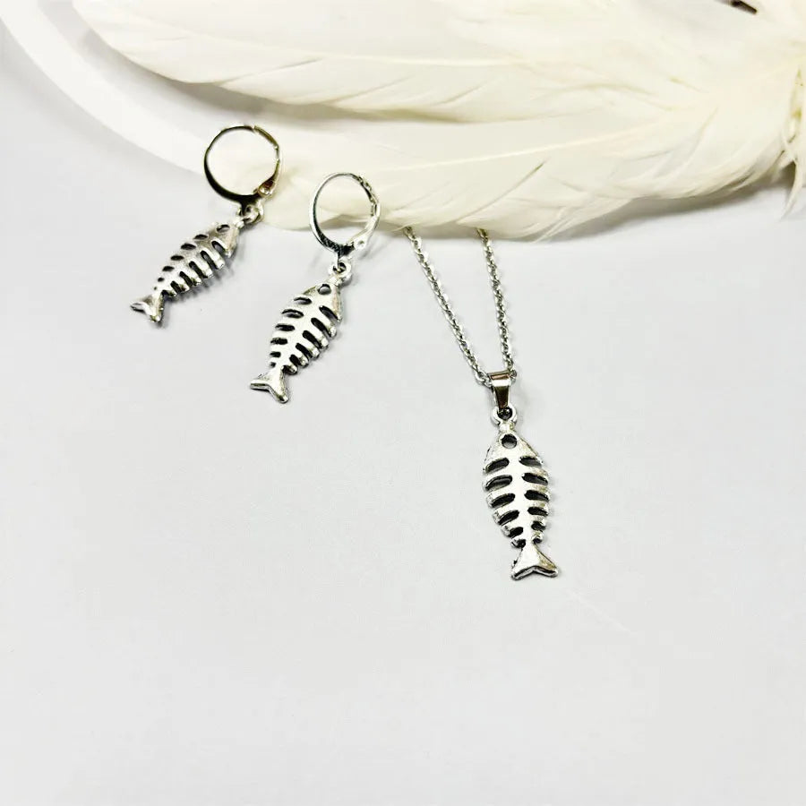 Women's fishbone pendant necklace and matching earrings set with adjustable chain on retro background