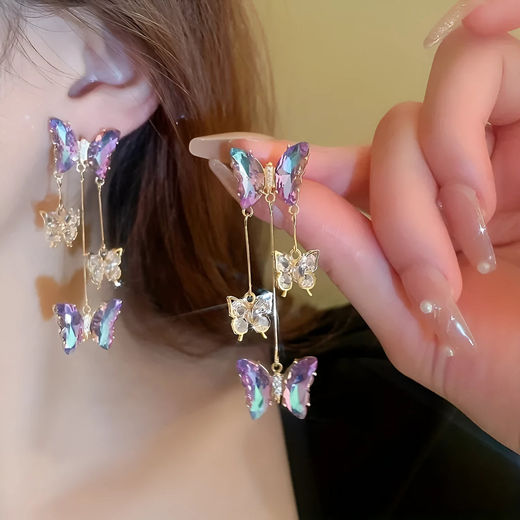 A pair of silver needle crystal flower and butterfly tassel earrings in a blue purple electroplated colour.