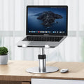Silver adjustable aluminium alloy laptop stand on a car back seat, showing height adjustment and ventilation holes.
