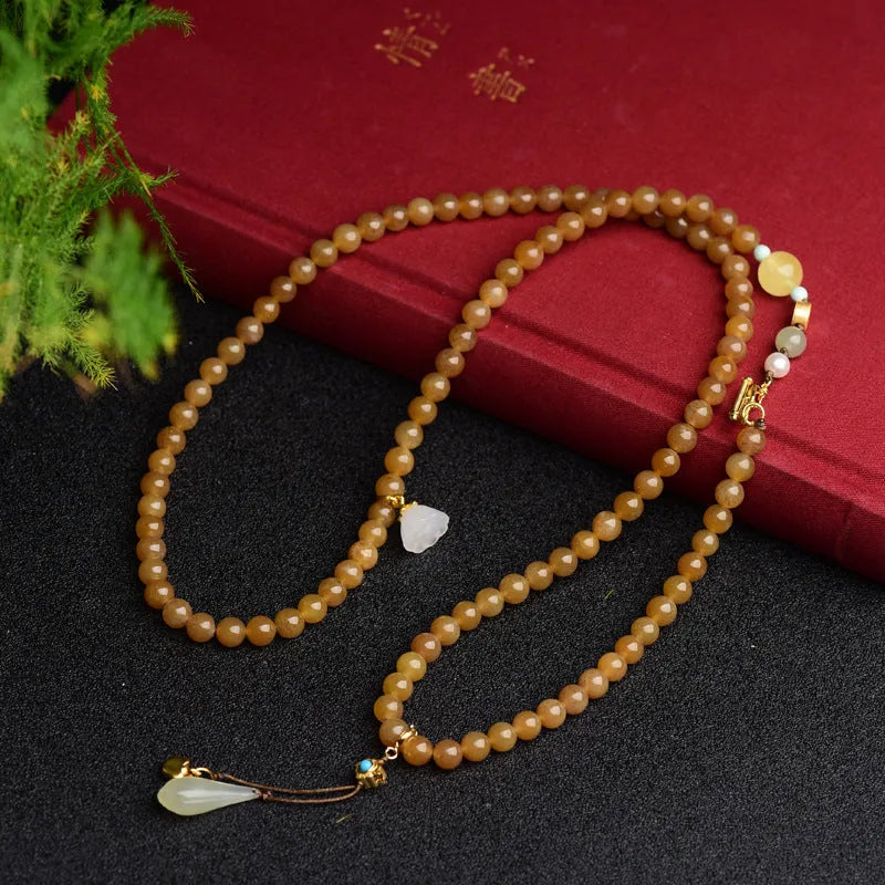Women's jade bracelet with 6mm round beads in clear water green featuring leaf accents