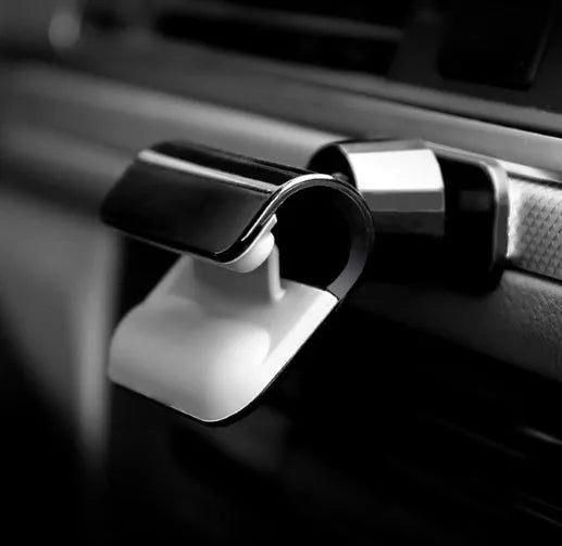 Black universal car phone holder with 360-degree rotating head on a car dashboard