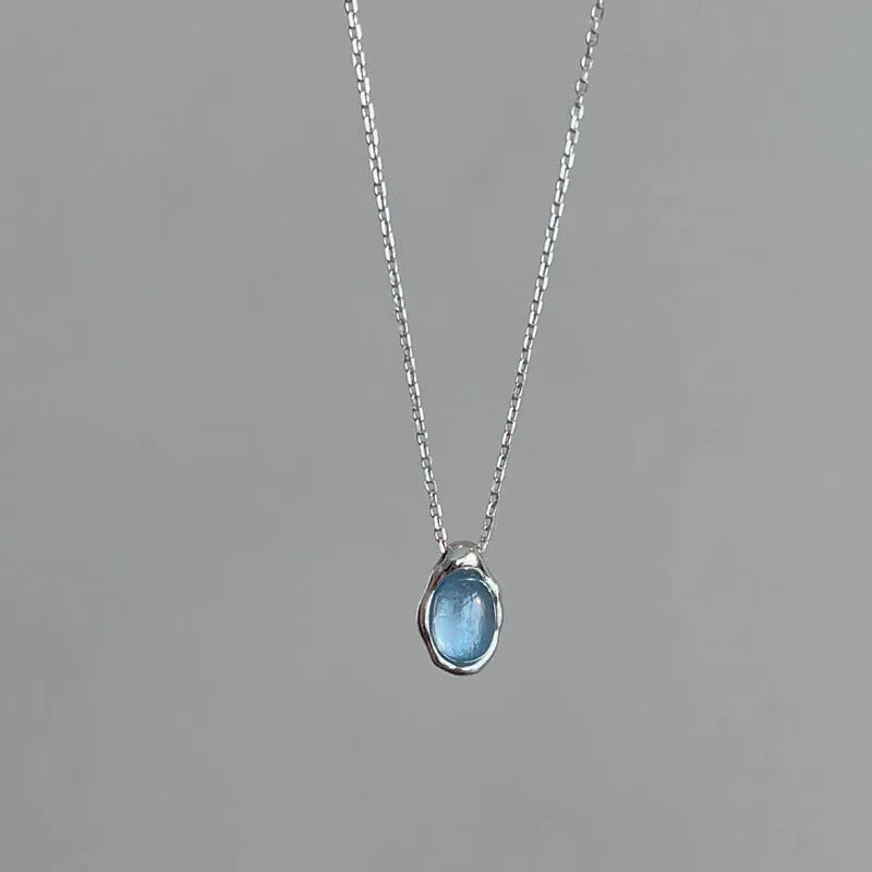 Geometric navy blue water drop pendant on an adjustable copper cross necklace for women.