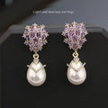 Close-up of a women's drop-shaped earring with inlaid pearl and zircon stones on an 18K gold-plated copper setting.