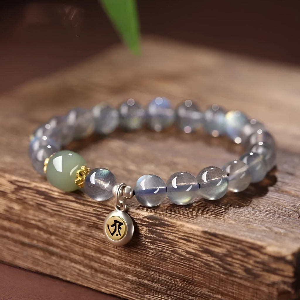 Close-up of a women's bracelet with 8mm moonstone beads and an electroplated Kwan-yin mouse charm.