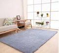 Soft white rectangular lambskin area rug with plush texture on a wooden floor.