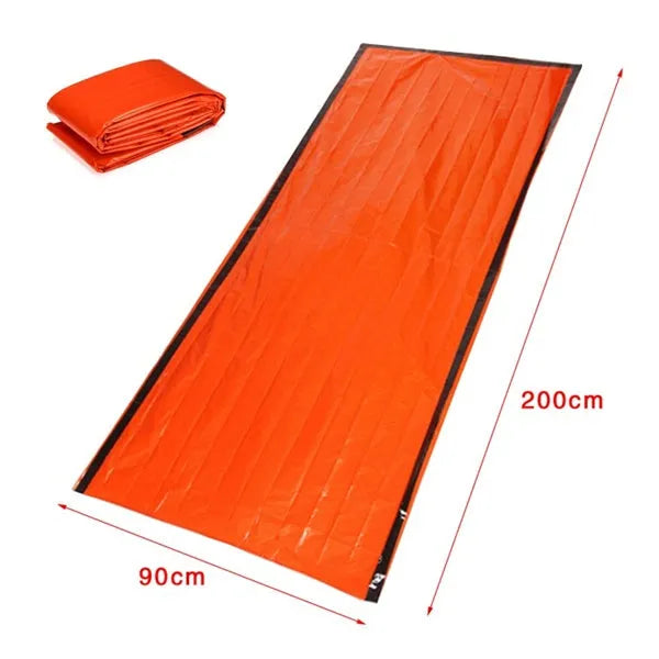 Orange PE aluminium film emergency sleeping bag folded and laid flat on outdoor ground