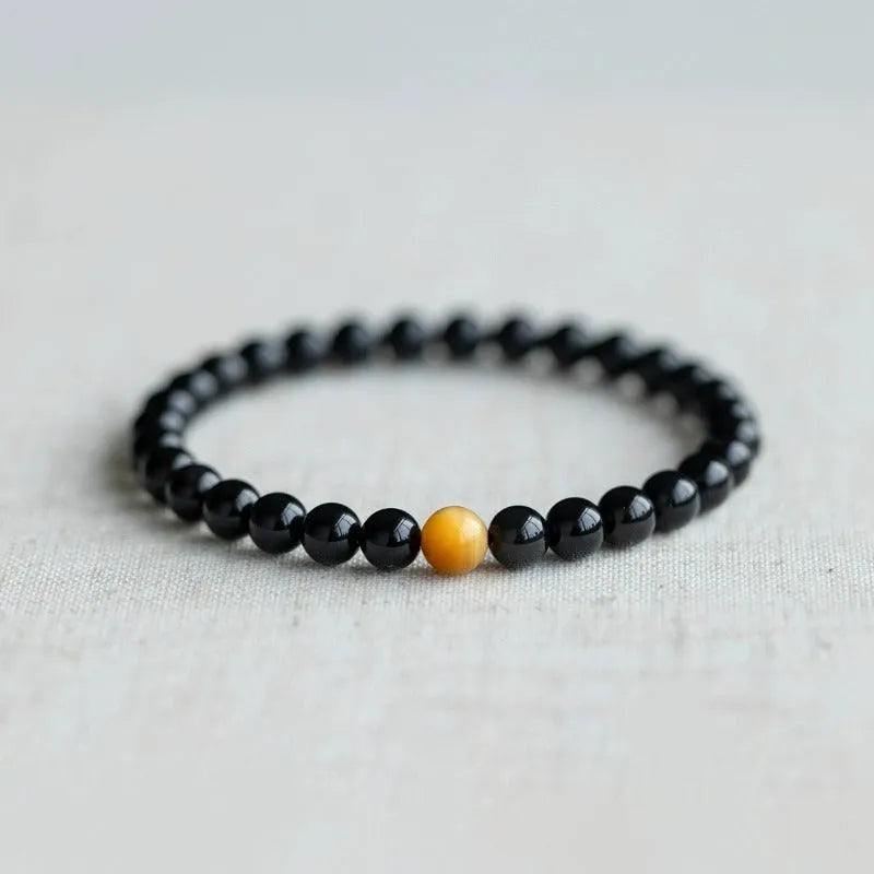 Natural black obsidian geometric bead bracelet on an adjustable string, showing 10mm bead size.