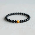 Natural black obsidian geometric bead bracelet on an adjustable string, showing 10mm bead size.