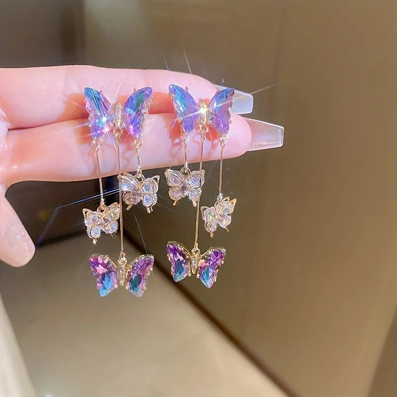 A pair of silver needle crystal flower and butterfly tassel earrings in a blue purple electroplated colour.