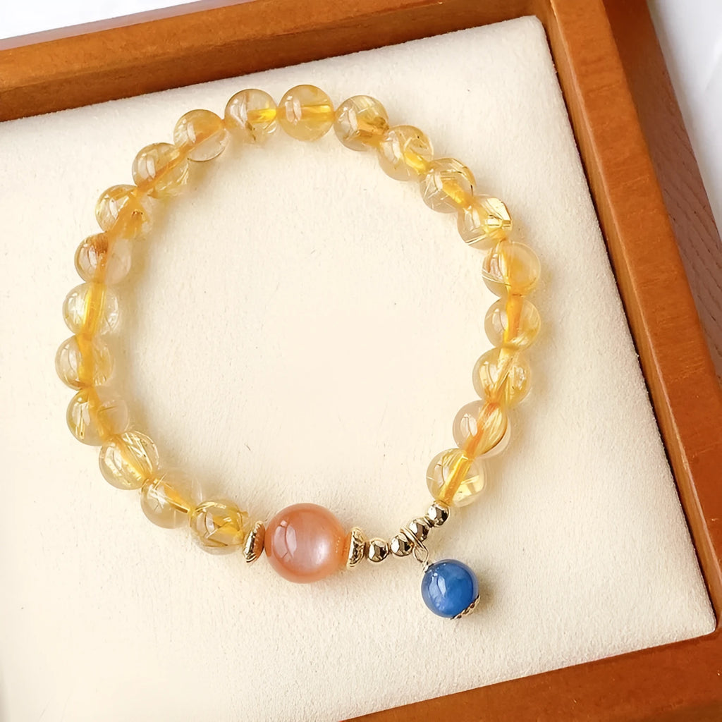 Gold rutilated quartz sunstone bracelet with diamond shapes and round beads on female wrist