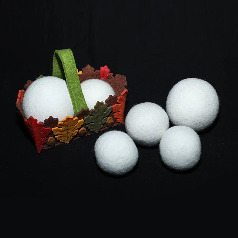 Handmade natural wool felt drying ball for laundry next to a plain cotton storage bag.