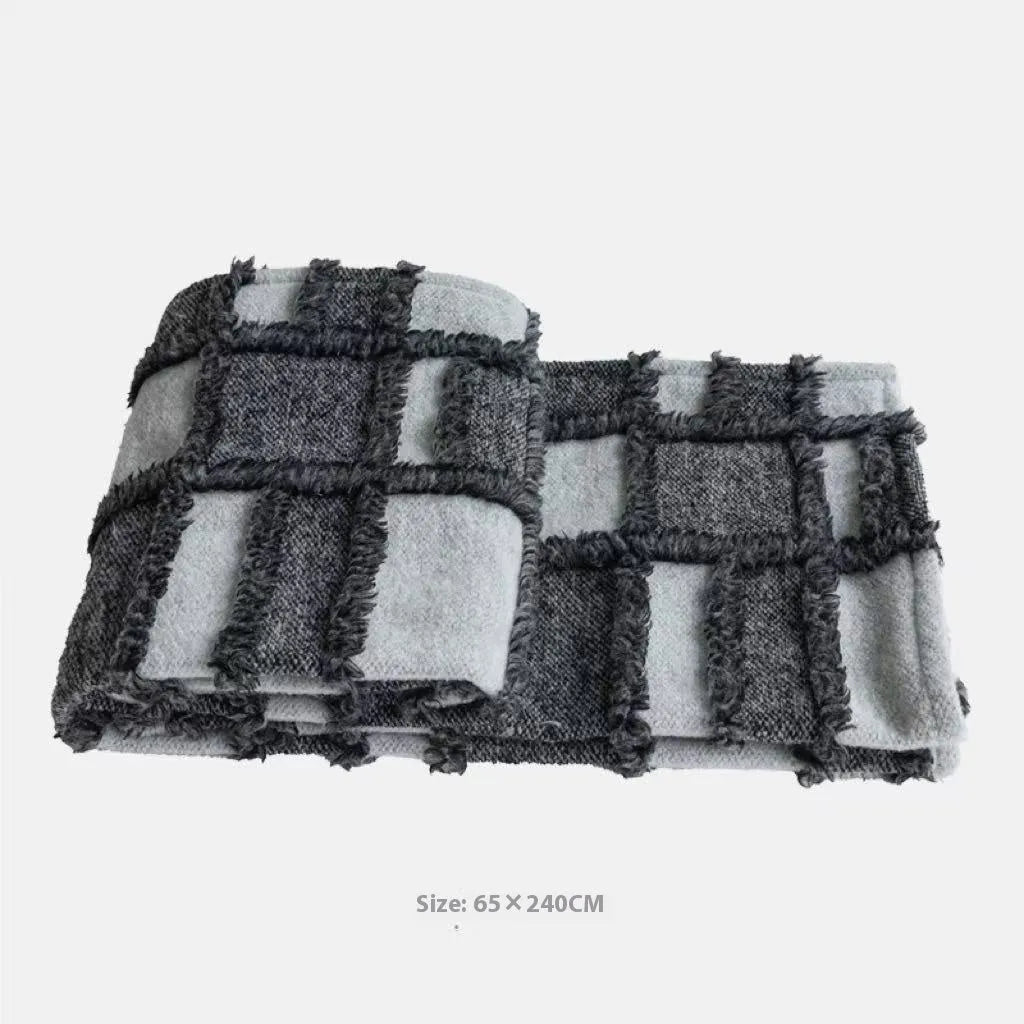 Modern minimalist grey and white plaid bed runner blanket set with matching pillowcase and leather round pillow on a bed.