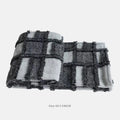 Modern minimalist grey and white plaid bed runner blanket set with matching pillowcase and leather round pillow on a bed.