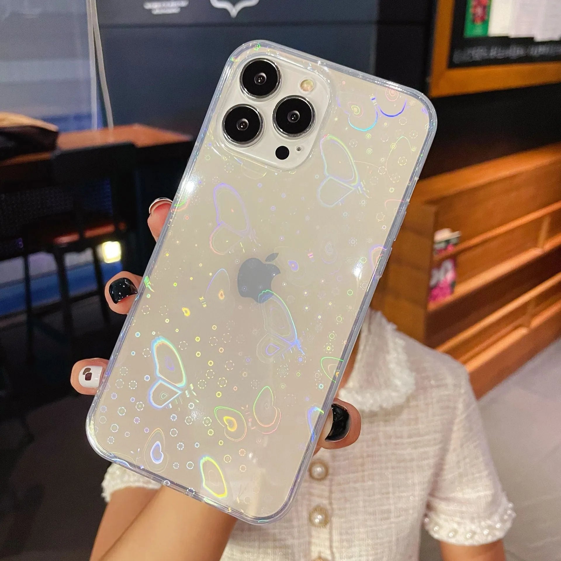 Transparent silicone iPhone case with laser-etched love heart design on a table.