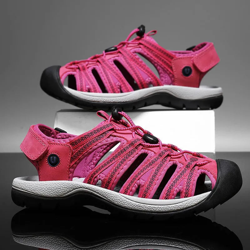 Women's black leather mesh toe box sandals with elastic band and rubber sole on a beach
