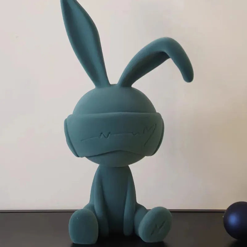 Resin rabbit table ornament with a suede blindfold in green, blue, or red colour options.