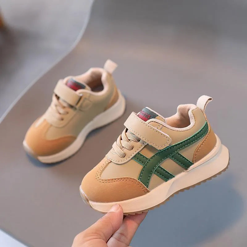 A pair of children's casual sneakers with a Velcro strap, shown in a neutral solid colour.