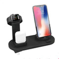 White headphone charging stand with dual USB ports on a wooden desk next to wireless headphones.