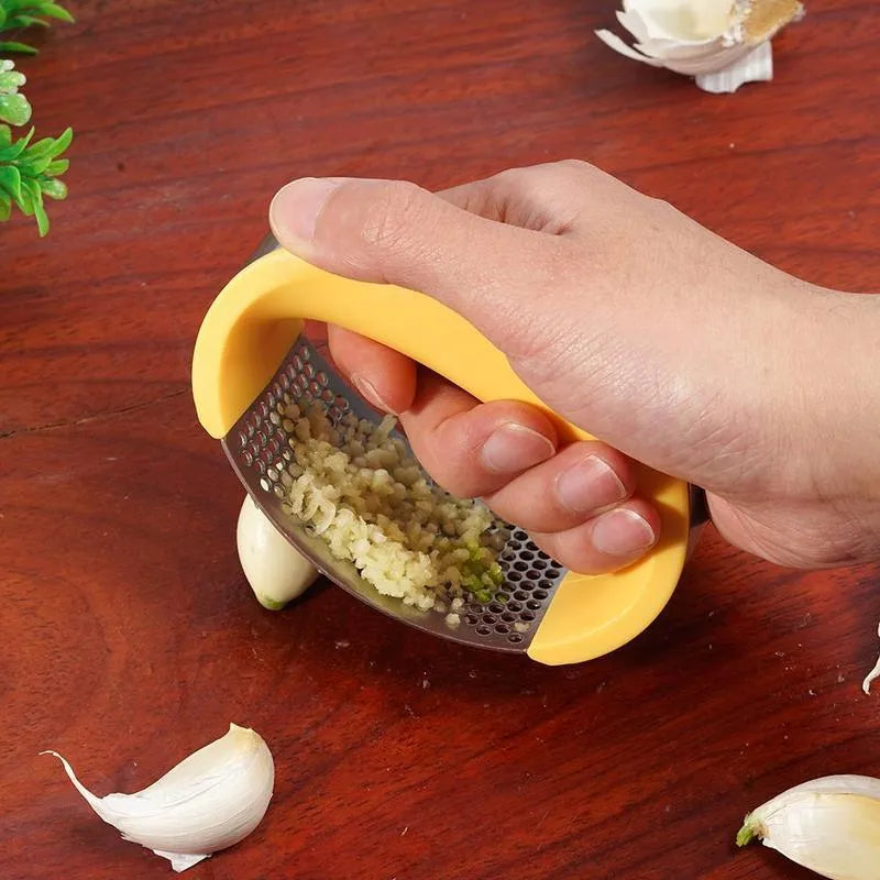 Stainless steel garlic press with ergonomic black handle on a kitchen counter.