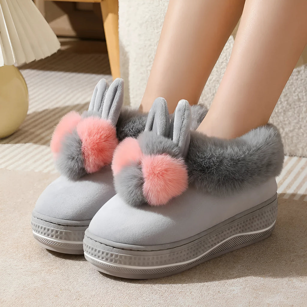 Grey plush high-heel winter slippers with a thick TPR sole on a wooden floor.