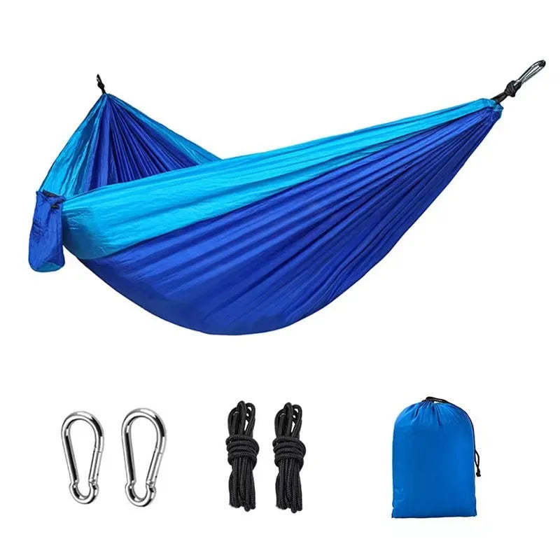 Blue nylon parachute cloth outdoor hammock hung between trees, showing its length and width.