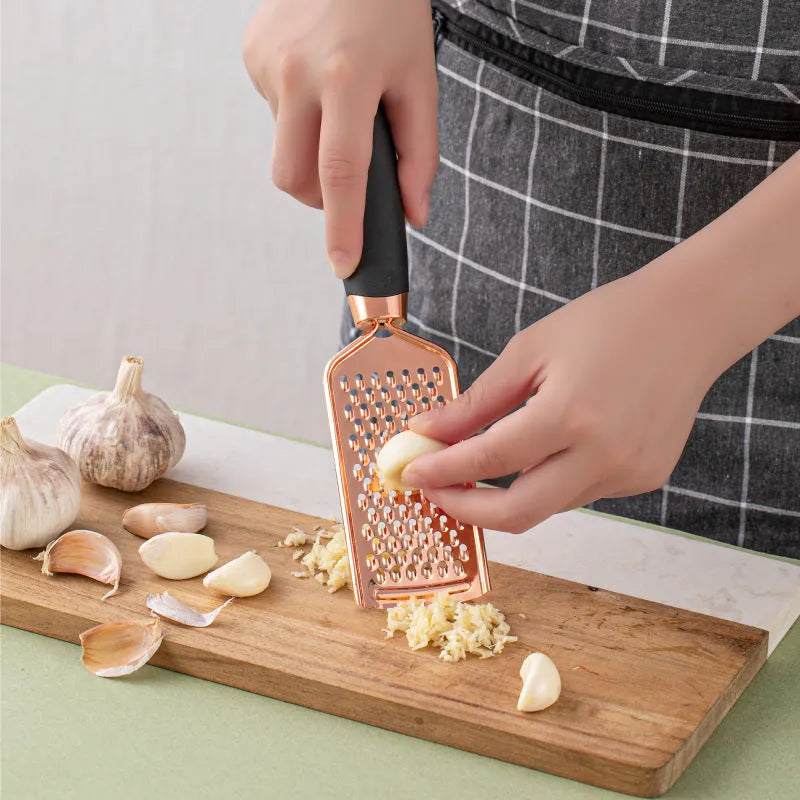 Seven-piece stainless steel kitchen tool set with copper handles on a cutlery rack, in rose gold colour.