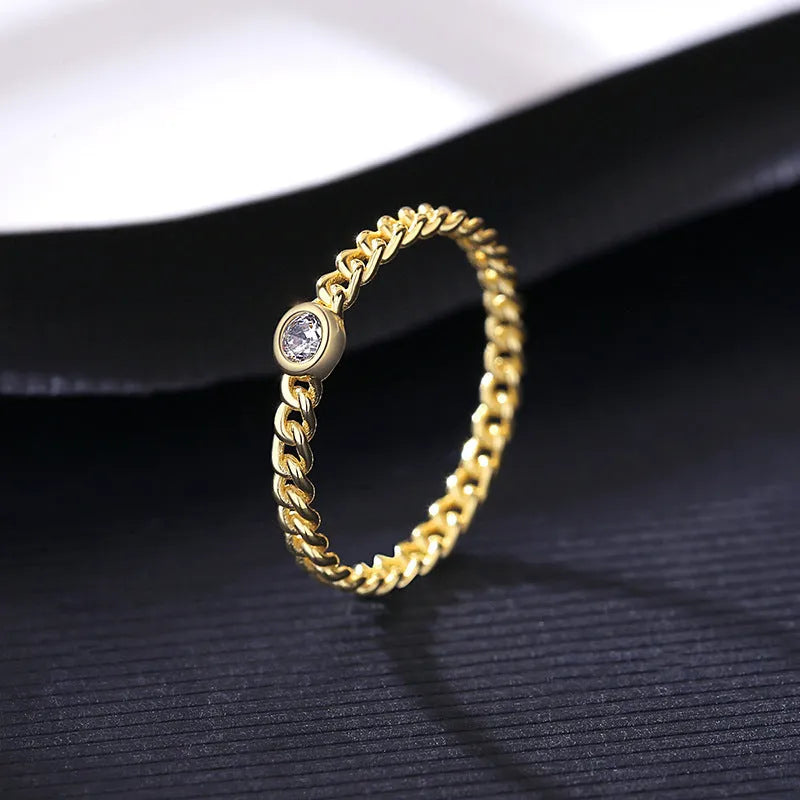 Close-up of 925 silver twist gold ring with geometric chain detail on a neutral background