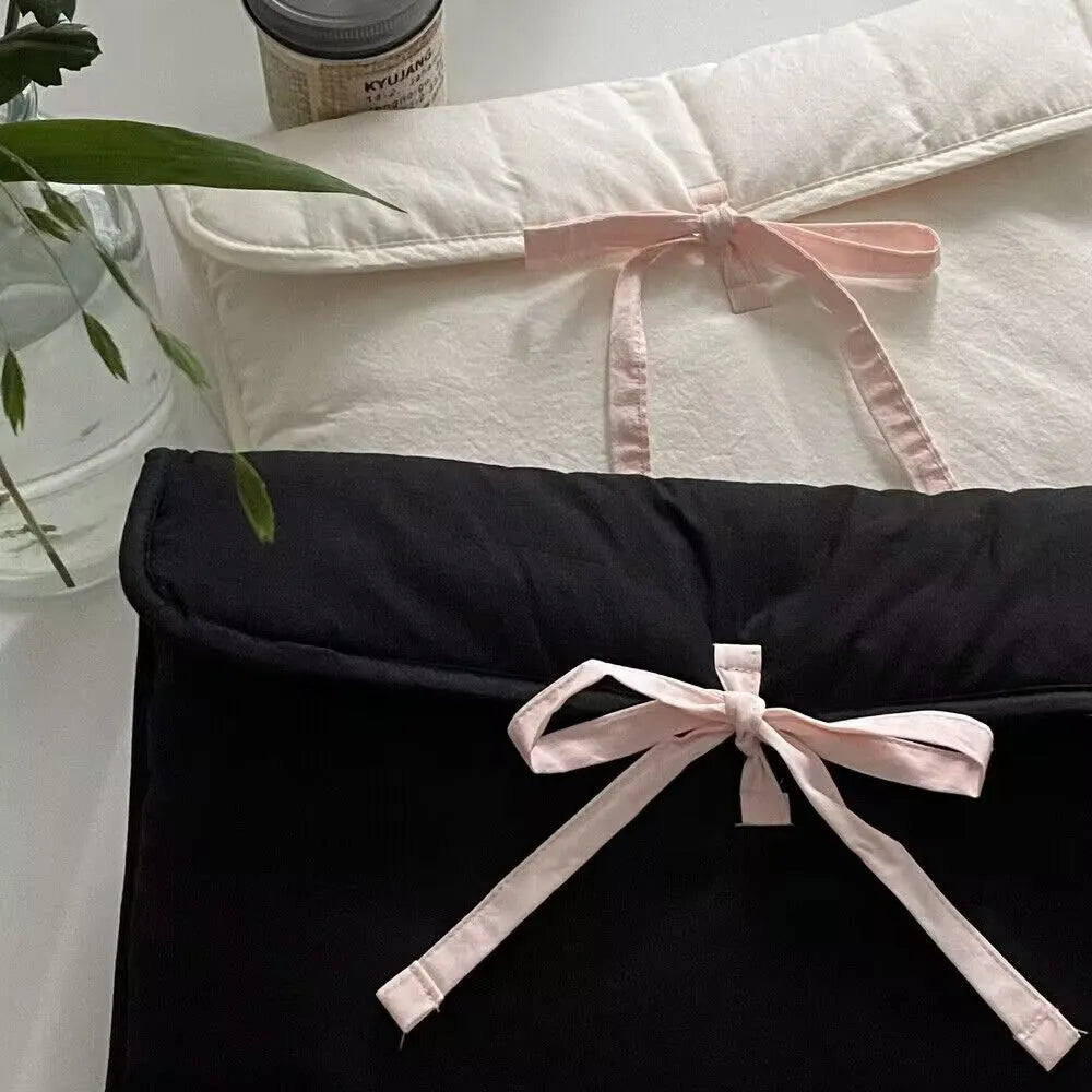 Black and white quilted laptop bag with a large ballet-style bow on the front.