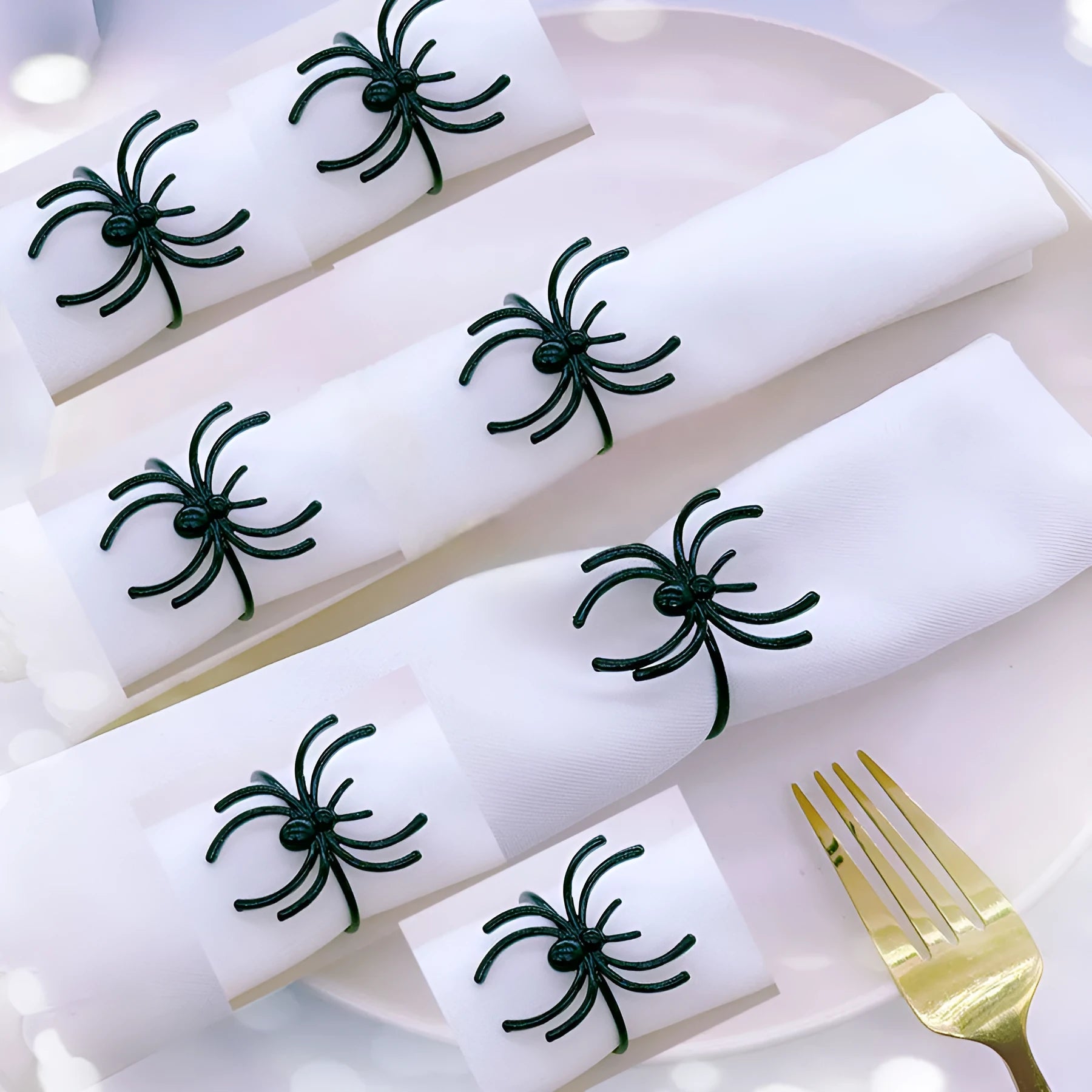 Set of six black metal spider-shaped napkin rings for Halloween table decorations.