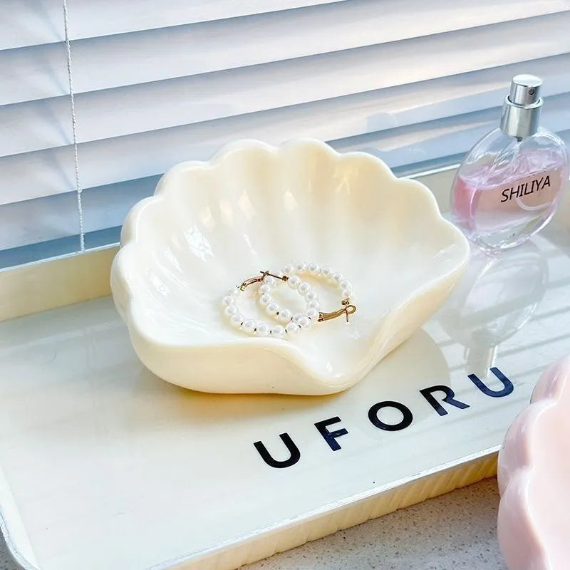 White plastic shell-shaped soap dish with drainage holes on a bathroom countertop